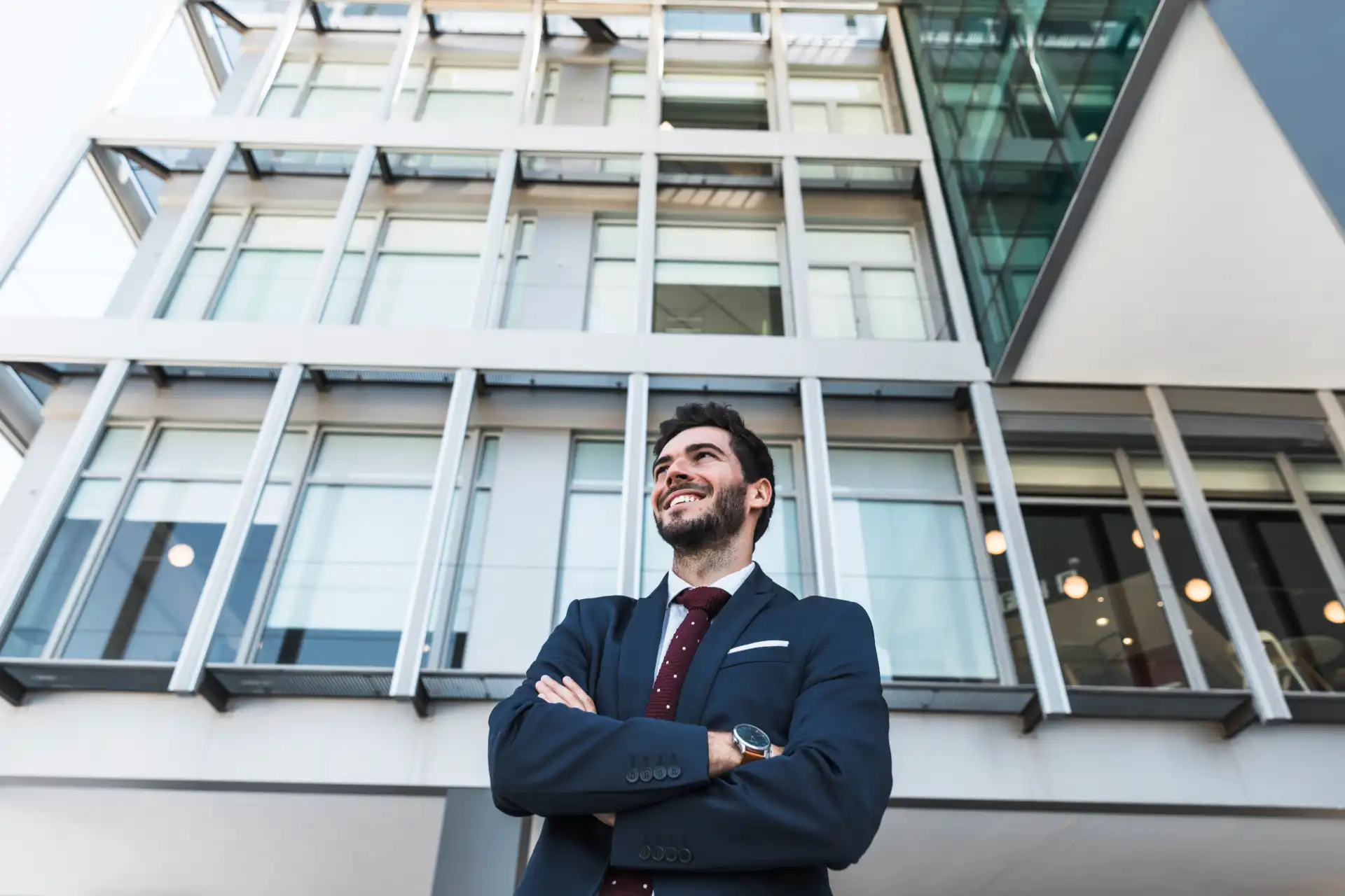 Homem de terno sorridente em frente a prédio moderno, simbolizando segurança e confiança em seguro condomínio para proteção patrimonial.